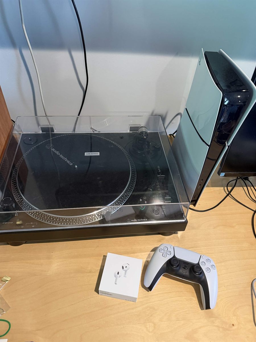 A console, controller, turntable and earbuds photographed together